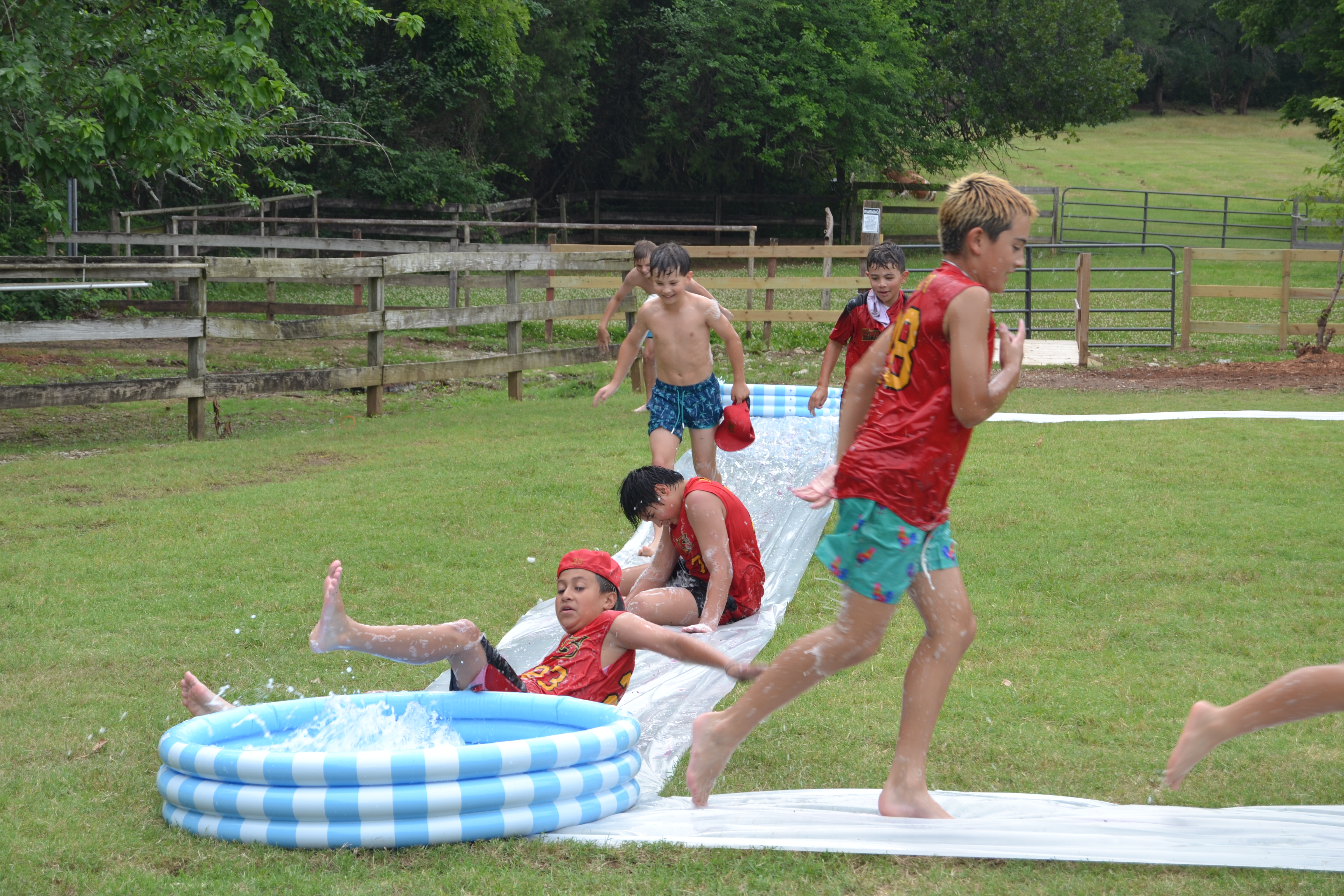 Campers racing down a slip-n-slide into a pool at Circle R Ranch