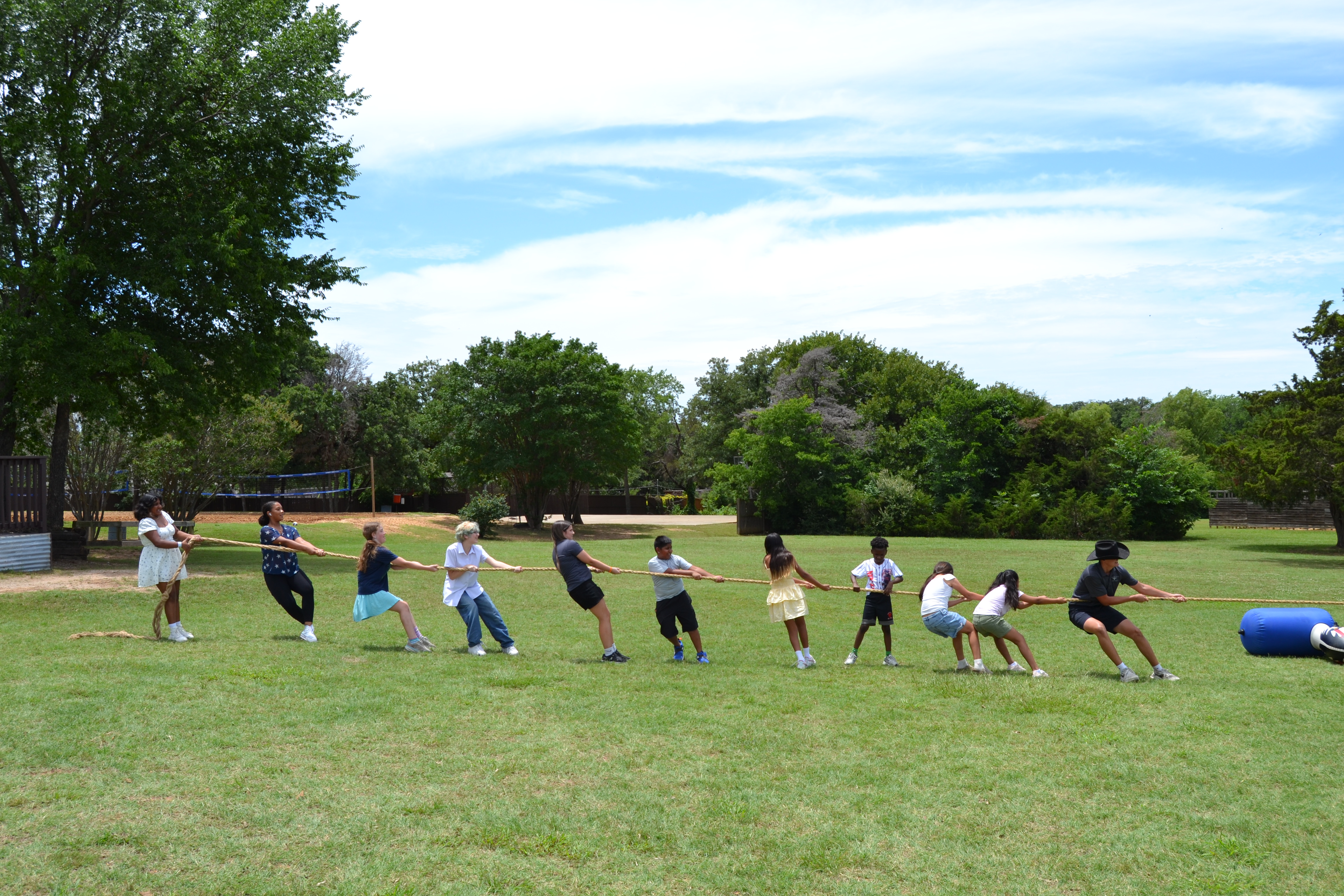 Campers playing tug-of-war on a grassy field at Circle R Ranch